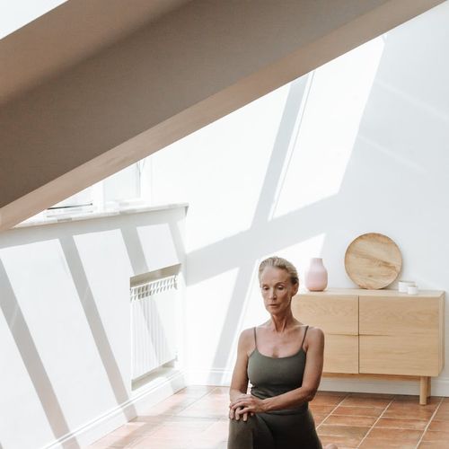 Person stretching gracefully in a bright, minimalist space.